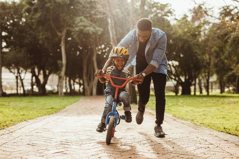 Pai ensinando o filho a andar de bicicleta no parque